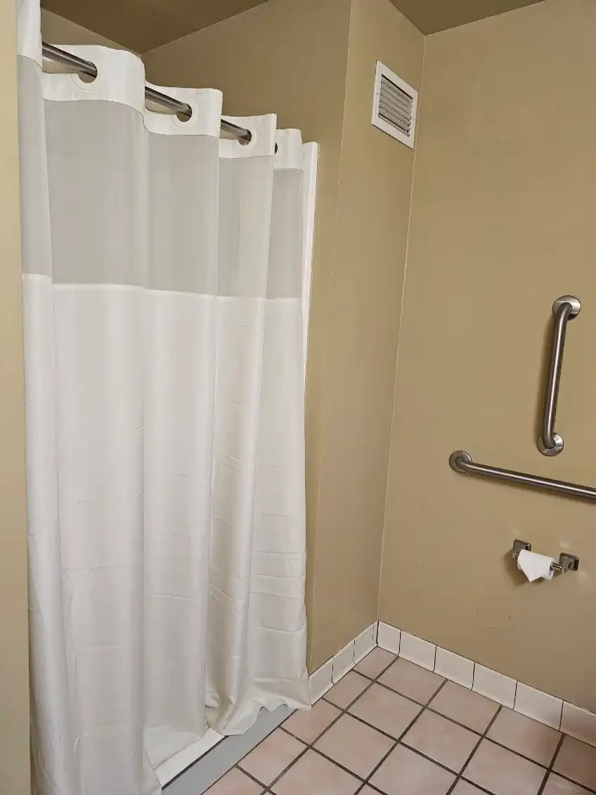 An en-suite bathroom with a curtained shower and grab bars