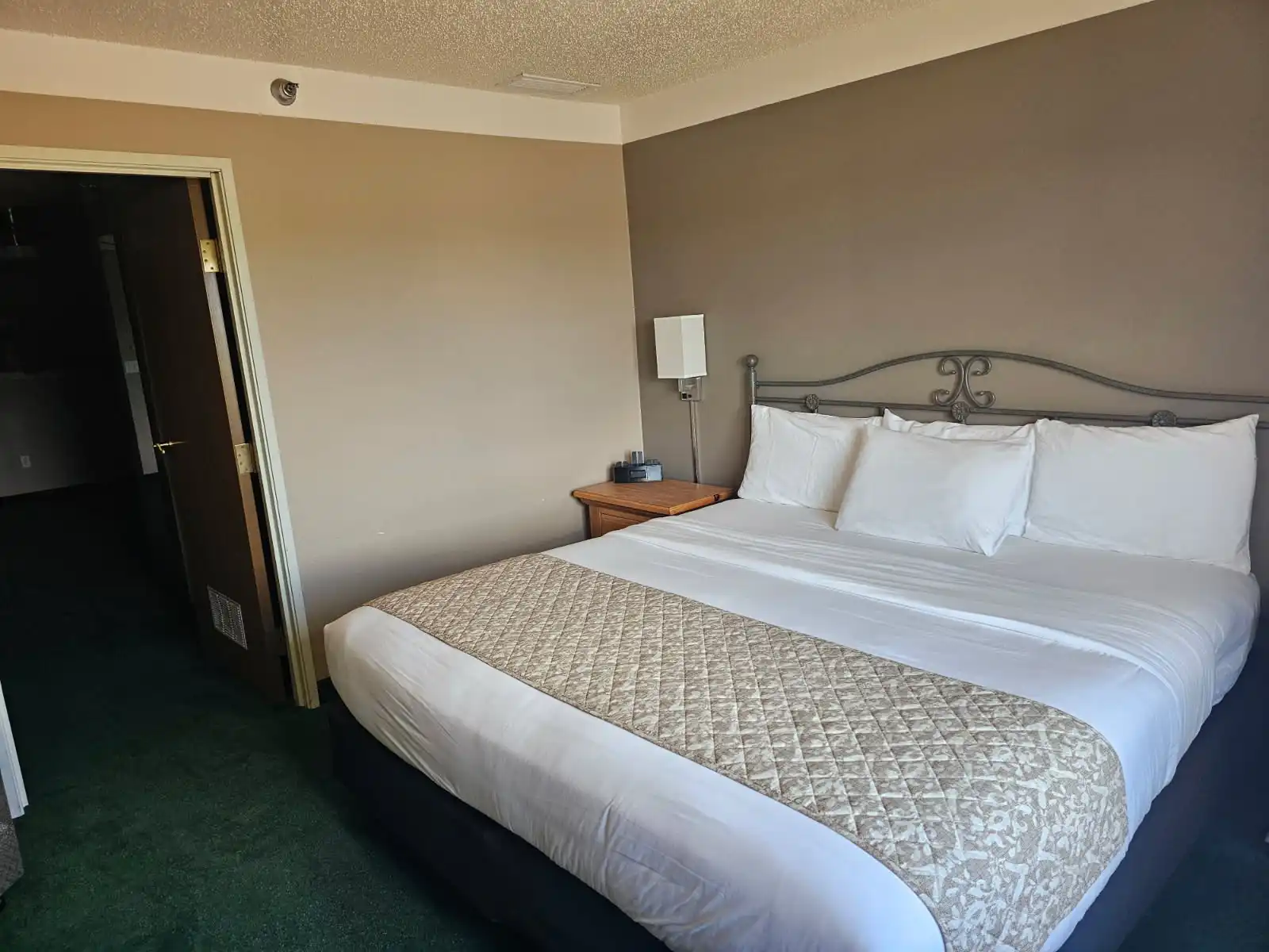 A guest room with a king bed and a wrought-iron headboard